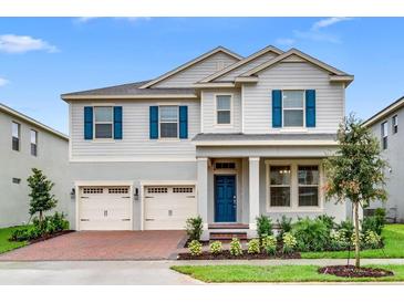 Charming two-story home featuring a blue front door, three-car garage, and manicured landscaping at 16146 Point Rock Dr, Winter Garden, FL 34787