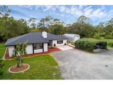 Charming single story home boasts mature landscaping, black accents, and a long gravel driveway at 2630 S Tanner Rd, Orlando, FL 32820