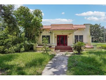 Charming home featuring a red-tiled roof, red front doors, and mature landscaping at 302 E Oakland Ave, Oakland, FL 34760
