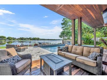 Inviting covered patio features a comfortable seating area, outdoor kitchen and a scenic lake view at 7801 Georgeann St, Winter Park, FL 32792