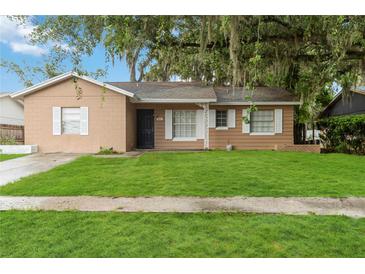 Charming single-story home with a well-manicured lawn and mature trees adding curb appeal at 8111 Esperanza St, Orlando, FL 32817
