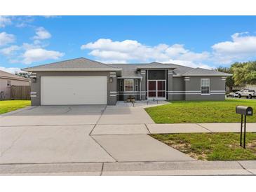 Charming single-story home featuring a gray exterior, well-manicured lawn, and an attached two-car garage at 906 Highland Crest Cir, Lake Wales, FL 33853