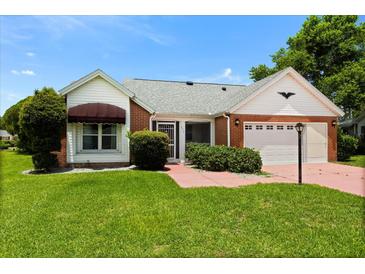 Charming brick and siding home with a well-manicured lawn and a covered entrance, showcasing curb appeal at 956 Chula Ct, Lady Lake, FL 32159