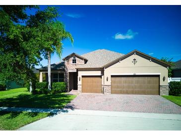 Charming single-Gathering home showcasing a three-car garage, manicured lawn, and beautiful landscaping at 12832 Sawgrass Pine Cir, Orlando, FL 32824