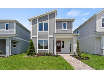 Modern two-story home with gray siding, stone accents, red door, and manicured lawn at 2046 Education St, St Cloud, FL 34771