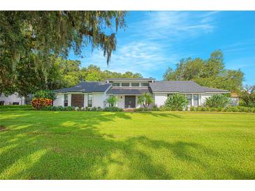 Stunning ranch-style home featuring a manicured lawn, a white brick facade, and mature landscaping at 3160 Whisper Wind Dr, St Cloud, FL 34771