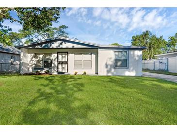 Well-maintained home with a fresh white exterior, landscaping, and a spacious green lawn at 7612 Pomelo Dr, Orlando, FL 32819