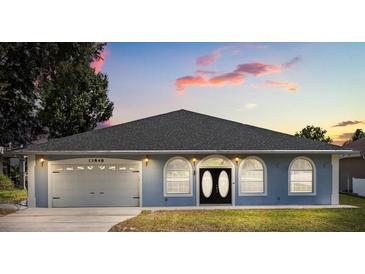 Charming single-story home showcasing a well-maintained lawn, two car garage and inviting arched windows at 13848 Vista Del Lago Blvd, Clermont, FL 34711