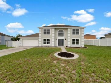 Two-story home featuring a front yard with green grass, complemented by a two-car garage and white fence at 1793 Western Hills Ln # N, Mascotte, FL 34753