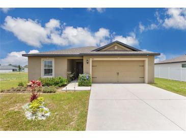 Charming single-story home showcasing a well-manicured lawn and welcoming two-car garage at 205 Cimarron Dr, Kissimmee, FL 34759