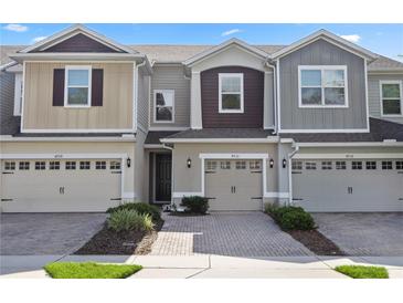 Charming townhome featuring a two-car garage, brick driveway, and beautifully landscaped front yard at 4733 Cliveden Loop, Sanford, FL 32773