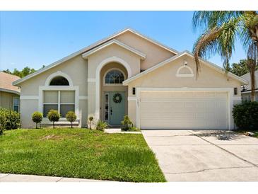 Charming single-Gathering home featuring a well-manicured lawn, a two-car garage, and an arched entryway at 5451 Los Palma Vista Dr, Orlando, FL 32837