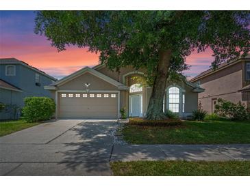 Charming home featuring a two-car garage, manicured lawn, and mature tree shading the front yard at 6720 Winder Lynne Ln, Orlando, FL 32819
