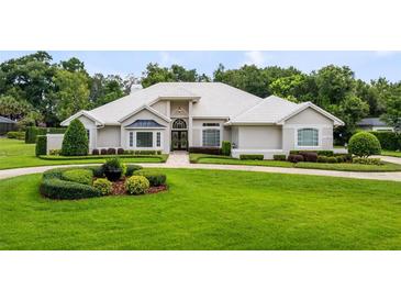 Stunning single-story home with a manicured front yard, a white tile roof, and elegant landscaping at 740 Bear Creek Cir, Winter Springs, FL 32708