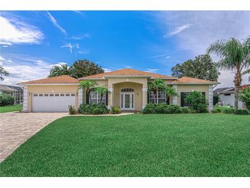 Inviting single-story home with manicured lawn, mature palms, and a paver driveway leading to the attached three-car garage at 800 Sterling Chase Dr, Port Orange, FL 32128