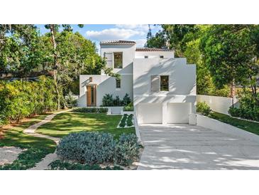 Stunning modern home with a lush green lawn, complemented by a two-car garage and white stucco exterior at 1150 Via Salerno, Winter Park, FL 32789