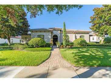 Beautiful one-story home with a landscaped front yard, brick walkway, and a well-manicured lawn at 11754 Waterstone Loop Dr, Windermere, FL 34786