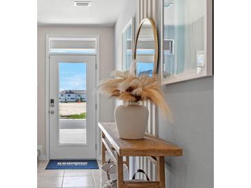 Bright entryway features a white door with glass and a console table with decorative vase at 1642 Rock Elm Rd, Davenport, FL 33837