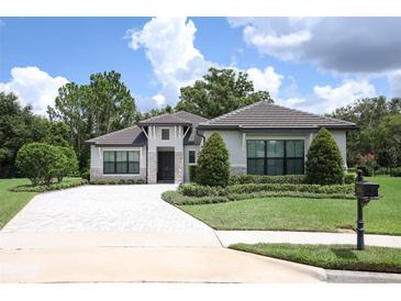 Charming single-story home with manicured lawn, neatly trimmed hedges, and a stone-paved driveway at 25974 High Hampton Cir, Sorrento, FL 32776