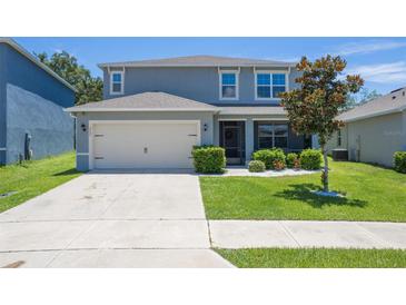Charming two-story home with manicured lawn, a two-car garage, and beautiful landscaping at 3759 Crimson Clover Dr, Mount Dora, FL 32757