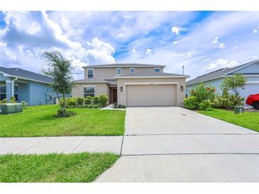 Two-story home with beige exterior, green lawn, and a two car garage at 5345 Tuscany Ln, Davenport, FL 33897