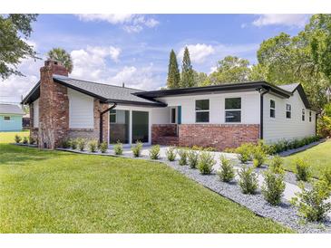 Charming home featuring a brick chimney, complemented by a lush green lawn and modern landscaping at 608 Cedar Ave, Holly Hill, FL 32117