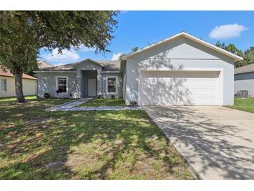 Charming single-story home with a well-maintained lawn and a two-car garage at 702 Pasteur Ln, Kissimmee, FL 34759