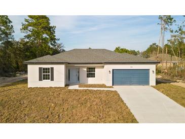 Charming single-story home featuring a blue garage door, complemented by a well-manicured lawn and a concrete driveway at 709 Marion Oaks Mnr, Ocala, FL 34473