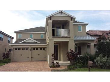 Two-story home featuring neutral stucco, a two-car garage, brick driveway, and a small balcony at 11837 Cave Run Ave, Windermere, FL 34786