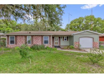 Charming single-story home featuring a brick facade, green siding, and a well-maintained front yard at 14402 Sw 34Th Terrace Rd, Ocala, FL 34473