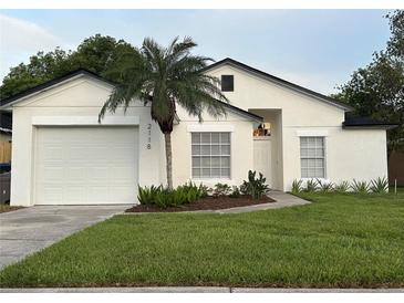 Charming single-story home featuring a well-manicured lawn, palm tree, and inviting front entrance at 2118 Donegan Pl, Orlando, FL 32826
