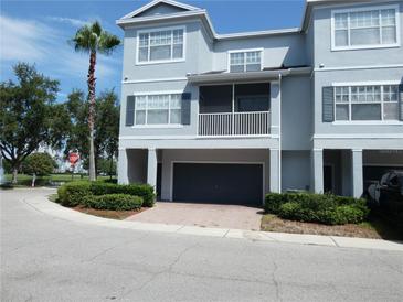 Well-maintained townhome featuring a two-car garage, a charming porch, and lush landscaping at 2406 Grand Central Pkwy # 14, Orlando, FL 32839