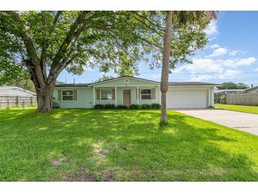 Charming single-story home with lush green lawn and mature trees creating a welcoming curb appeal at 323 Scotland Dr, Daytona Beach, FL 32117