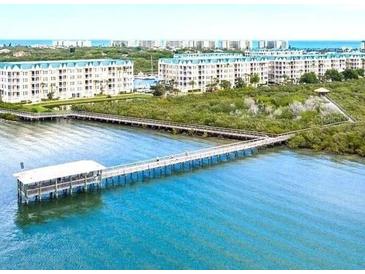 Scenic view of condos with a beautiful pier on the water, surrounded by lush greenery at 4628 Harbour Village Blvd # 2308, Ponce Inlet, FL 32127