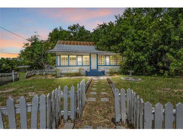 Charming single-story home with blue trim, a quaint picket fence, and lush surrounding trees at 516 Tybee Pl, Orlando, FL 32829