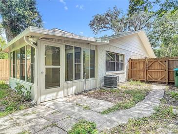 A home's cozy backyard with a patio, screened enclosure, and wooden fence under a clear, blue sky at 809 Sugar House Blvd, Port Orange, FL 32129
