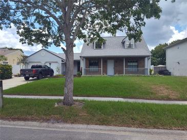 Charming home with a brick facade, covered front porch, manicured lawn, and a detached garage at 8850 Pine Bay Ct, Orlando, FL 32825