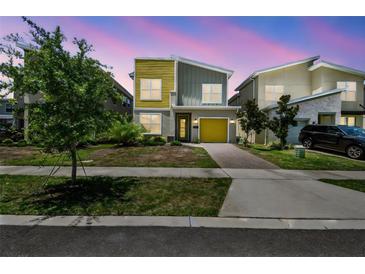 Striking two-story home with modern design, lush landscaping, and a yellow accent garage door at 4367 Rhyme St, Kissimmee, FL 34746