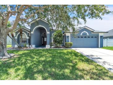Charming single-story home featuring a manicured lawn, arched entryway and an attached two-car garage at 1031 Seneca Trl, St Cloud, FL 34772