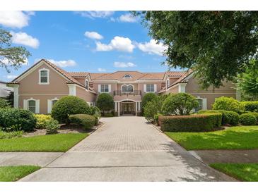 Inviting, two-story house with a red tile roof, manicured shrubs and a brick driveway at 10915 Emerald Chase Dr, Orlando, FL 32836