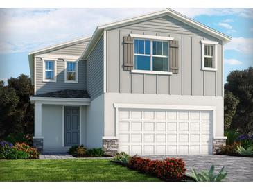Two-story home featuring a gray exterior, complemented by a white garage door and manicured landscaping at 3674 Portsmouth Ln, Haines City, FL 33844