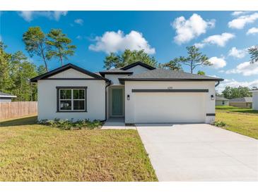 Beautiful white house with black accents, a two-car garage, and a well-maintained lawn at 6291 Sw 133Rd Street Road, Ocala, FL 34473