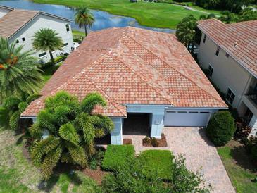 Charming home with a red tile roof, lush landscaping, and a view of the community lake and golf course at 9979 Winnington St, Orlando, FL 32832