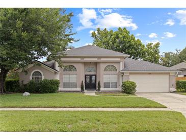 Charming single-story home with arched windows, lush lawn, mature trees, and a welcoming double-door entrance at 1103 Lake Legro Ct, Orlando, FL 32835