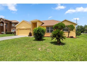 Charming yellow home featuring a lush green lawn, landscaped front yard, and two-car garage at 1457 Teal Dr, Kissimmee, FL 34759