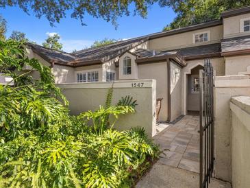 Charming home exterior with manicured landscaping and a private gated entrance to the front door at 1547 Farrindon Cir # 1547, Lake Mary, FL 32746