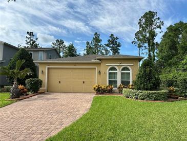 Charming single-story home with a brick driveway, well-manicured lawn, and lush landscaping at 1573 Amber Leaf Cir, Ocoee, FL 34761