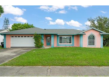 Charming single-story home with a well-maintained lawn and attached garage, features a whimsical pink and teal exterior at 2309 Cilantro Dr, Orlando, FL 32837