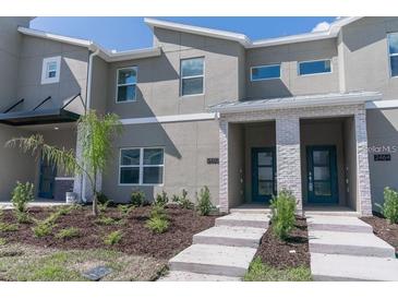 Modern townhome featuring a gray facade with a landscaped front yard and decorative stone accents around the entryway at 2460 Reading Trl, Kissimmee, FL 34746