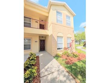 Two-story condo with a private balcony and a well-manicured lawn with shrubs and mulched flower beds at 2816 Club Cortile Cir # A, Kissimmee, FL 34746